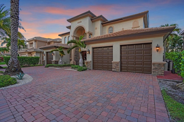 718 Edgebrook Ln, West Palm Beach, FL 33411 - mediterranean / spanish home featuring decorative driveway, stucco siding, stone siding, a garage, and a tiled roof
