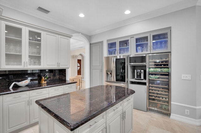 718 Edgebrook Ln, West Palm Beach, FL 33411 - kitchen with wine cooler, arched walkways, stainless steel fridge, crown molding, and glass insert cabinets