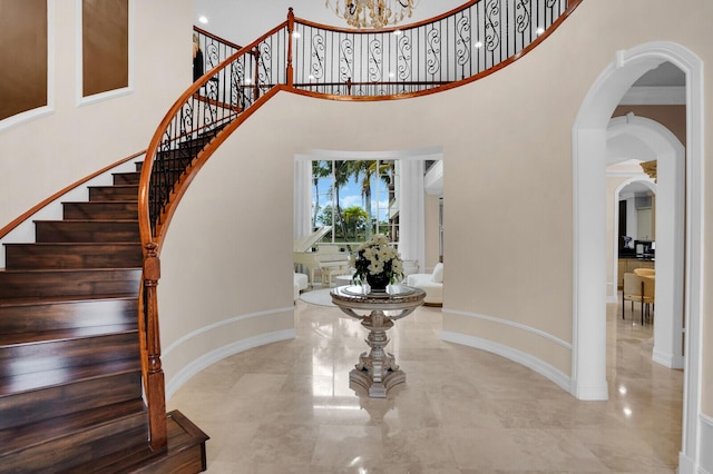 718 Edgebrook Ln, West Palm Beach, FL 33411 - foyer entrance featuring a towering ceiling, stairs, a chandelier, arched walkways, and marble tiled floors
