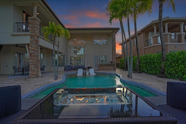 718 Edgebrook Ln, West Palm Beach, FL 33411 - pool at dusk with an outdoor pool, a patio area, an outdoor fire pit, and a ceiling fan