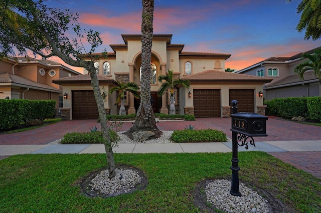 718 Edgebrook Ln, West Palm Beach, FL 33411 - mediterranean / spanish-style home featuring decorative driveway, stucco siding, a garage, a front lawn, and stone siding