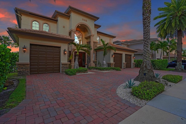 718 Edgebrook Ln, West Palm Beach, FL 33411 - mediterranean / spanish-style home featuring decorative driveway, stone siding, stucco siding, and a garage
