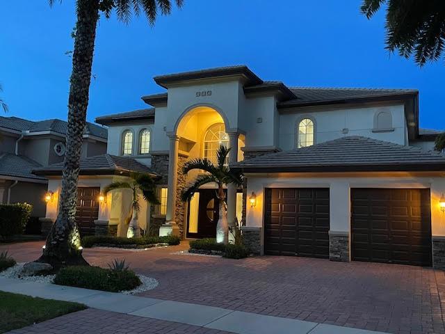 718 Edgebrook Ln, West Palm Beach, FL 33411 - mediterranean / spanish-style home featuring an attached garage, decorative driveway, stucco siding, and stone siding