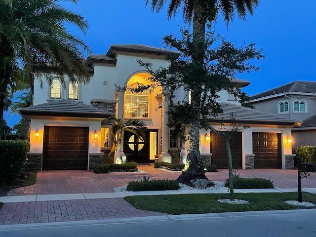 718 Edgebrook Ln, West Palm Beach, FL 33411 - mediterranean / spanish-style house featuring decorative driveway, an attached garage, stone siding, and stucco siding