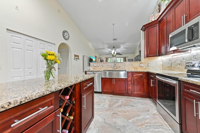 8404 Long Bay, West Palm Beach, FL 33411 - kitchen with appliances with stainless steel finishes, reddish brown cabinets, tasteful backsplash, and high vaulted ceiling
