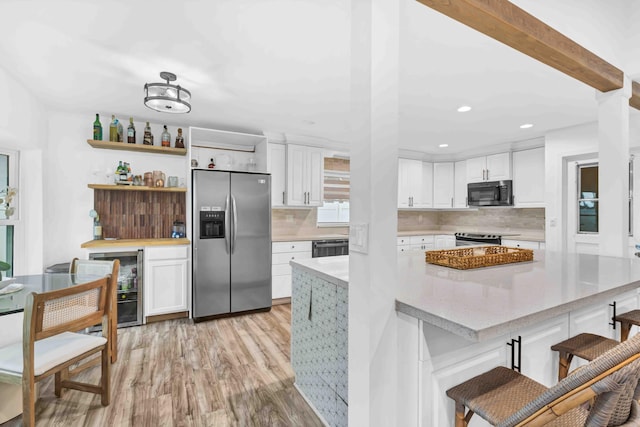 108 Timber Run E, Riviera Beach, FL 33407 - kitchen with appliances with stainless steel finishes, light wood-type flooring, white cabinetry, light countertops, and backsplash