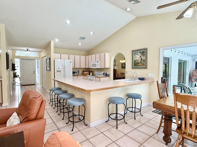 13021 150th Ct N, Jupiter, FL 33478 - kitchen featuring white appliances, a kitchen bar, light tile patterned floors, a ceiling fan, and arched walkways