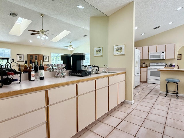 13021 150th Ct N, Jupiter, FL 33478 - kitchen featuring white appliances, a skylight, vaulted ceiling, a textured ceiling, and light countertops