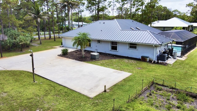 13021 150th Ct N, Jupiter, FL 33478 - back of property with stucco siding, a metal roof, concrete driveway, a yard, and a lanai