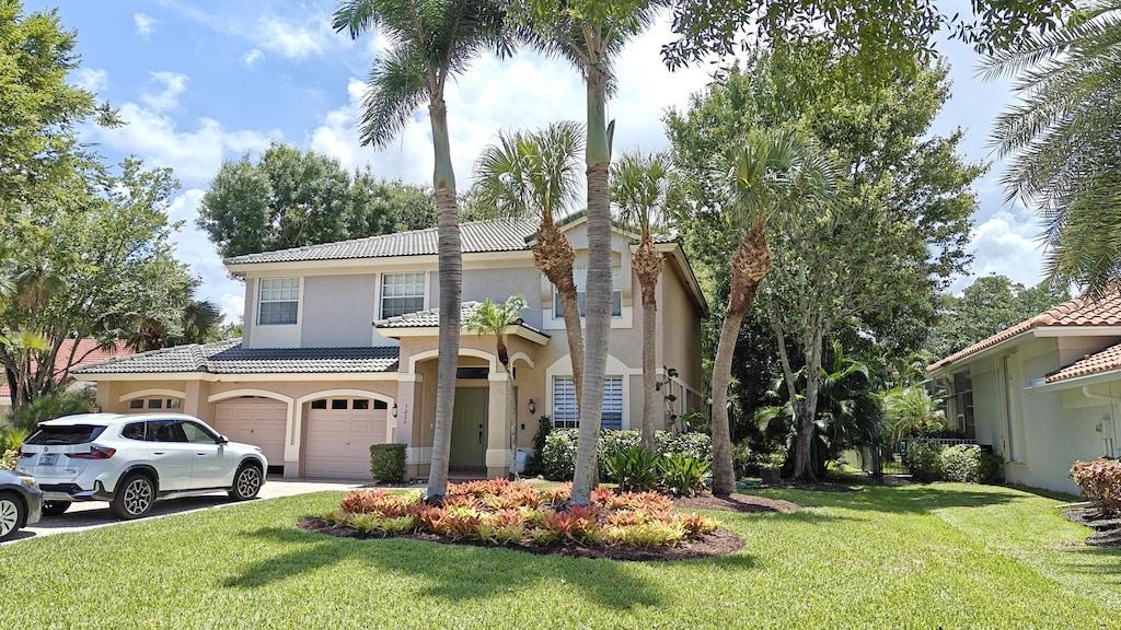 5020 SW Elk River Ct, Palm City, FL 34990 - mediterranean / spanish house with a tile roof, an attached garage, stucco siding, a front yard, and concrete driveway