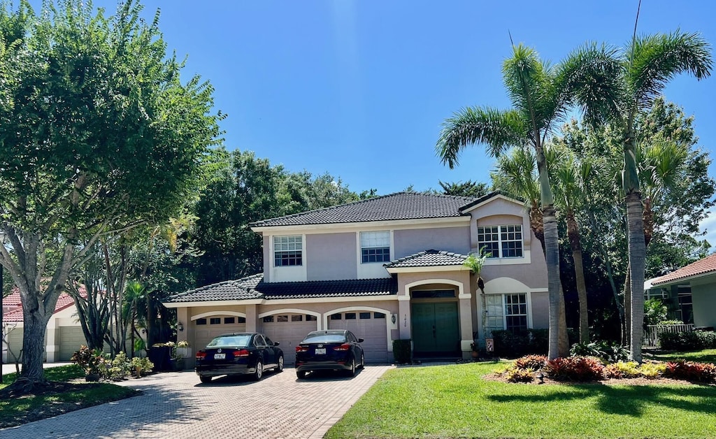5020 SW Elk River Ct, Palm City, FL 34990 - mediterranean / spanish-style house with stucco siding, a tile roof, decorative driveway, a front yard, and a garage