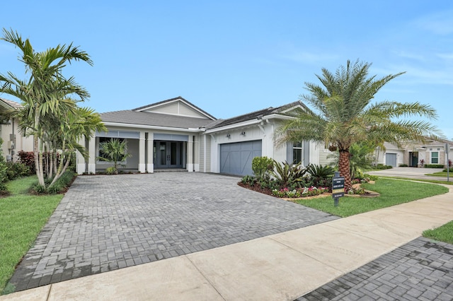10051 Timber Creek Way, Palm Beach Gardens, FL 33412 - ranch-style home with an attached garage, decorative driveway, french doors, stucco siding, and a front yard