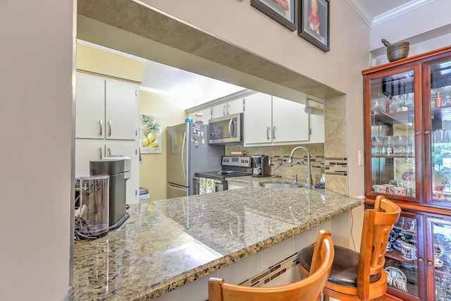 4452 NE Ocean Blvd Unit C2, Jensen Beach, FL 34957 - kitchen with appliances with stainless steel finishes, ornamental molding, light stone countertops, white cabinetry, and decorative backsplash