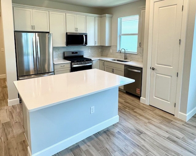 1236 Harper Way Unit 57, Vero Beach, FL 32960 - kitchen with appliances with stainless steel finishes, backsplash, light wood finished floors, a center island, and light countertops