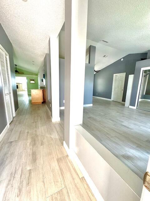 2681 SW Tanforan Blvd, Port Saint Lucie, FL 34953 - hall featuring lofted ceiling, a textured ceiling, and light wood finished floors