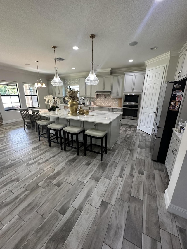 13106 Jeter Creek Dr, Riverview, FL 33579 - kitchen featuring appliances with stainless steel finishes, a large island, decorative backsplash, dark wood-style flooring, and a textured ceiling