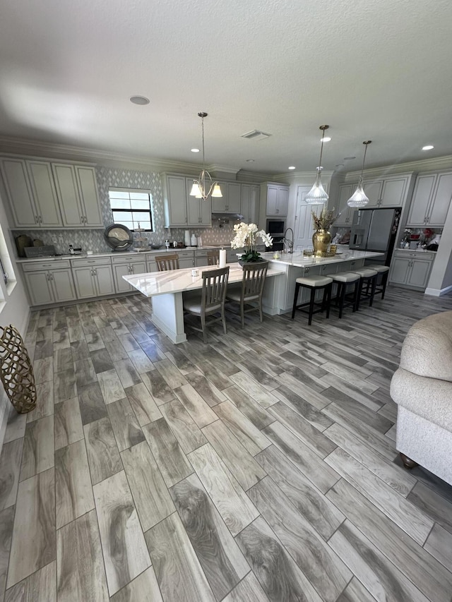 13106 Jeter Creek Dr, Riverview, FL 33579 - kitchen featuring gray cabinetry, a breakfast bar, a spacious island, tasteful backsplash, and ornamental molding
