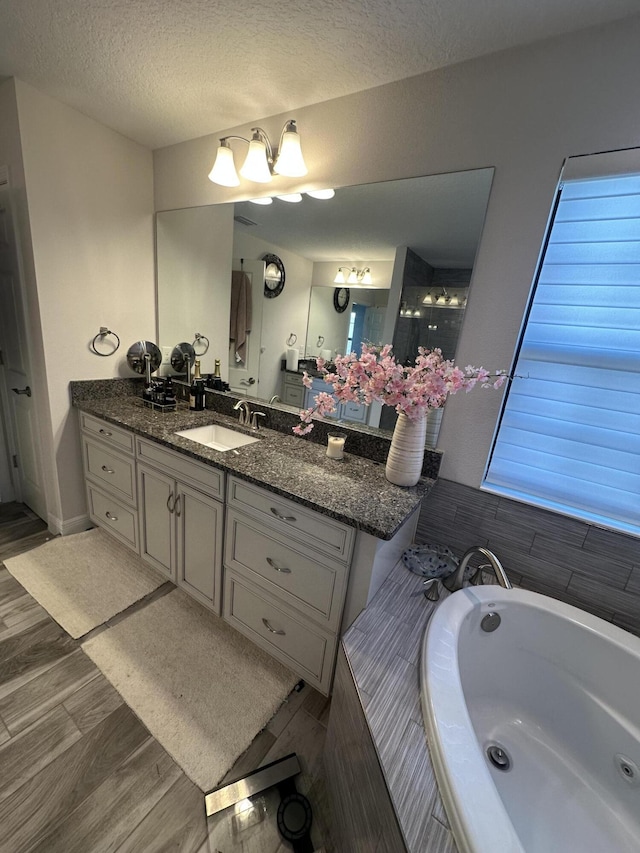 13106 Jeter Creek Dr, Riverview, FL 33579 - bathroom featuring a garden tub, vanity, wood finished floors, and a textured ceiling