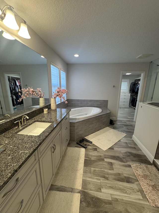 13106 Jeter Creek Dr, Riverview, FL 33579 - bathroom featuring a spacious closet, a garden tub, vanity, a textured ceiling, and recessed lighting