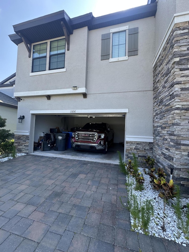 13106 Jeter Creek Dr, Riverview, FL 33579 - view of side of home featuring stone siding, a garage, stucco siding, and decorative driveway