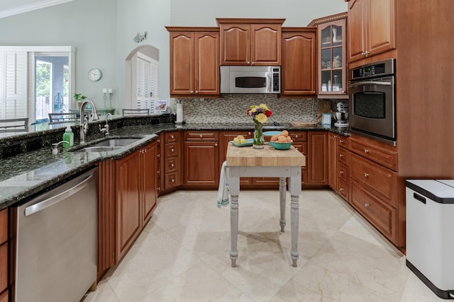 1101 SW Kickaboo Rd, Port Saint Lucie, FL 34953 - kitchen with stainless steel appliances, decorative backsplash, dark stone counters, crown molding, and glass insert cabinets