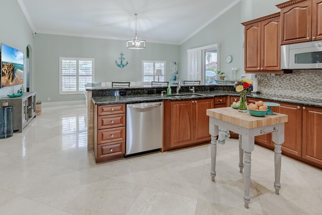 1101 SW Kickaboo Rd, Port Saint Lucie, FL 34953 - kitchen featuring appliances with stainless steel finishes, crown molding, a peninsula, lofted ceiling, and dark stone counters