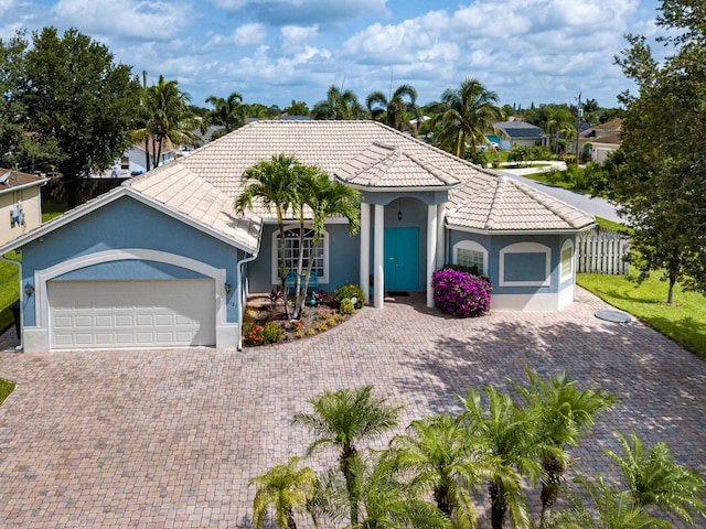 1101 SW Kickaboo Rd, Port Saint Lucie, FL 34953 - mediterranean / spanish home with stucco siding, a tiled roof, an attached garage, and decorative driveway