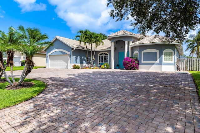 1101 SW Kickaboo Rd, Port Saint Lucie, FL 34953 - mediterranean / spanish house featuring stucco siding, decorative driveway, an attached garage, and a tiled roof