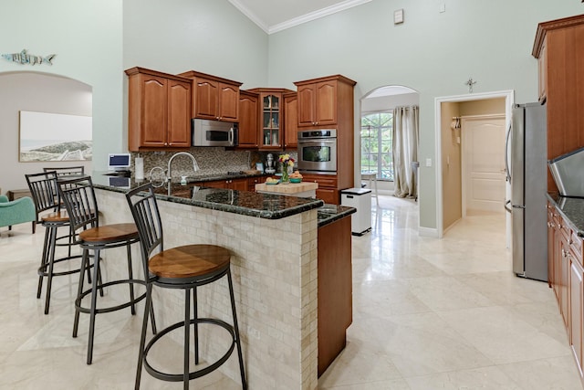1101 SW Kickaboo Rd, Port Saint Lucie, FL 34953 - kitchen with stainless steel appliances, arched walkways, crown molding, a towering ceiling, and a peninsula