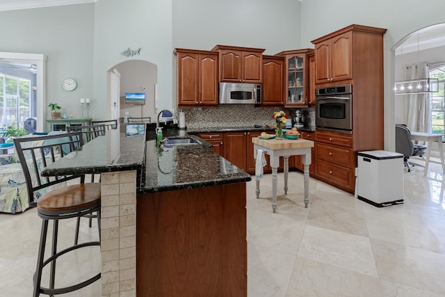 1101 SW Kickaboo Rd, Port Saint Lucie, FL 34953 - kitchen featuring stainless steel appliances, a towering ceiling, a breakfast bar, backsplash, and arched walkways