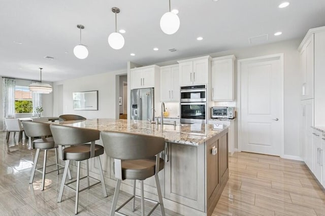 242 Tresana Blvd Unit 70, Jupiter, FL 33478 - kitchen with appliances with stainless steel finishes, a spacious island, white cabinets, light stone countertops, and hanging light fixtures