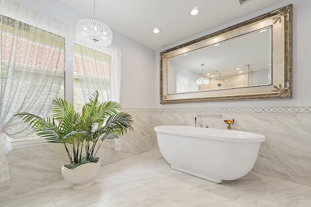 13709 Rivoli Dr, Palm Beach Gardens, FL 33410 - bathroom featuring a freestanding tub, marble finish flooring, tile walls, a chandelier, and recessed lighting