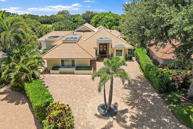 13709 Rivoli Dr, Palm Beach Gardens, FL 33410 - mediterranean / spanish-style home featuring a tiled roof, stucco siding, and roof mounted solar panels