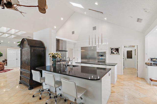 13709 Rivoli Dr, Palm Beach Gardens, FL 33410 - kitchen featuring a spacious island, high vaulted ceiling, appliances with stainless steel finishes, a skylight, and white cabinetry