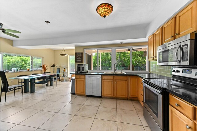 3560 SW 63rd Ave, Miramar, FL 33023 - kitchen featuring stainless steel appliances, ceiling fan, dark countertops, light tile patterned floors, and brown cabinets