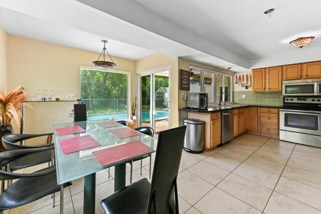 3560 SW 63rd Ave, Miramar, FL 33023 - kitchen with appliances with stainless steel finishes, dark countertops, decorative backsplash, light tile patterned flooring, and decorative light fixtures