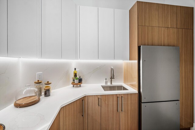 17 NW 15th St, Delray Beach, FL 33444 - kitchen featuring freestanding refrigerator, light countertops, backsplash, and white cabinetry