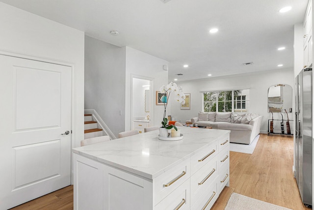 674 NW Library Commons Way, Boca Raton, FL 33432 - kitchen with a kitchen island, stainless steel fridge with ice dispenser, white cabinetry, light stone counters, and light wood finished floors