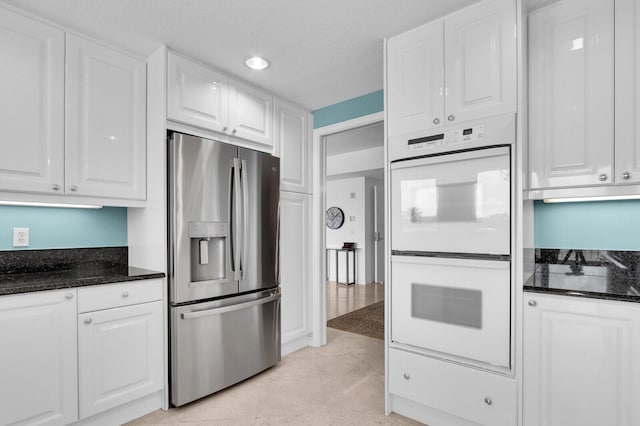 700 Ocean Royale Way Unit 202, Juno Beach, FL 33408 - kitchen featuring stainless steel refrigerator with ice dispenser, white double oven, white cabinetry, dark stone counters, and recessed lighting