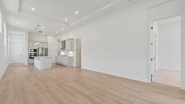 212 SE Via Sangro, Port Saint Lucie, FL 34952 - unfurnished living room with light wood finished floors, recessed lighting, and a raised ceiling