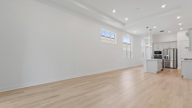 212 SE Via Sangro, Port Saint Lucie, FL 34952 - unfurnished living room with a raised ceiling, recessed lighting, and light wood-type flooring