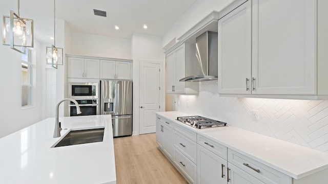 212 SE Via Sangro, Port Saint Lucie, FL 34952 - kitchen featuring stainless steel appliances, wall chimney range hood, decorative backsplash, light countertops, and light wood-style floors