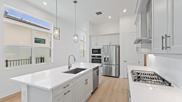 212 SE Via Sangro, Port Saint Lucie, FL 34952 - kitchen featuring stainless steel appliances, backsplash, light countertops, wall chimney exhaust hood, and light wood-type flooring