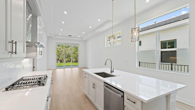 212 SE Via Sangro, Port Saint Lucie, FL 34952 - kitchen featuring appliances with stainless steel finishes, open floor plan, wall chimney exhaust hood, light wood-style flooring, and white cabinets