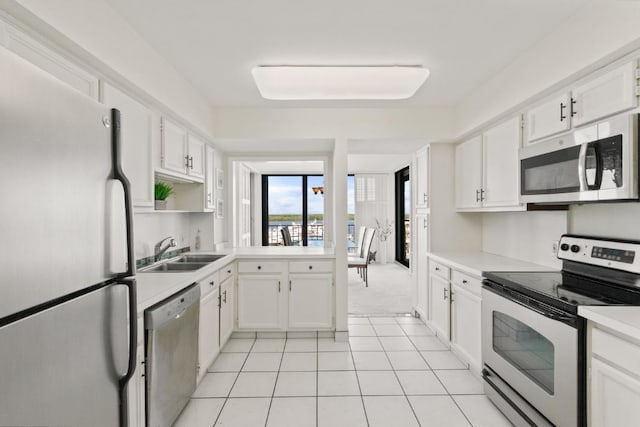 120 Lakeshore Dr Unit 735, North Palm Beach, FL 33408 - kitchen with stainless steel appliances, light countertops, white cabinets, light tile patterned floors, and light carpet