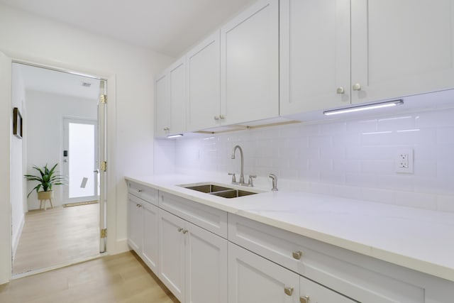 1893 Circle Dr, North Palm Beach, FL 33408 - kitchen featuring backsplash, light wood-style flooring, light stone countertops, and white cabinetry