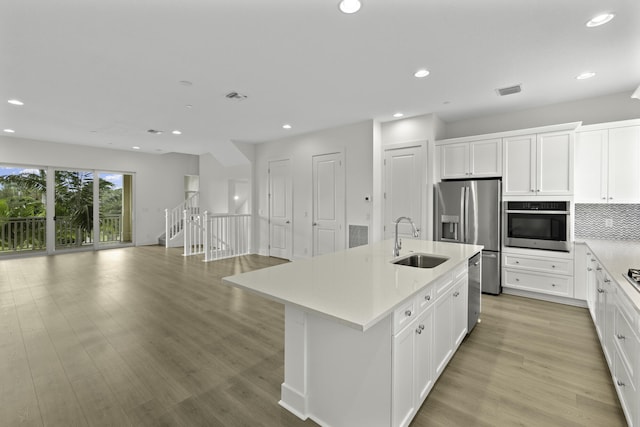 5143 Beckman Ter, Palm Beach Gardens, FL 33418 - kitchen with stainless steel appliances, light countertops, recessed lighting, a center island with sink, and light wood-style flooring