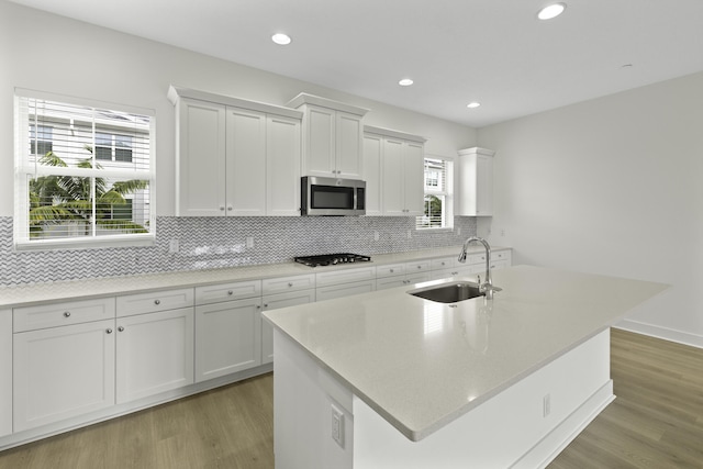 5143 Beckman Ter, Palm Beach Gardens, FL 33418 - kitchen with stainless steel microwave, light wood-style flooring, white cabinets, decorative backsplash, and recessed lighting