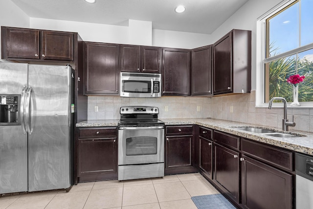 8274 Cascada Isles Dr, Cooper City, FL 33024 - kitchen with stainless steel appliances, light stone counters, light tile patterned flooring, backsplash, and dark brown cabinets