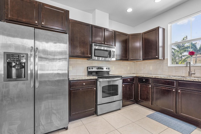 8274 Cascada Isles Dr, Cooper City, FL 33024 - kitchen with appliances with stainless steel finishes, light tile patterned floors, light stone counters, dark brown cabinetry, and recessed lighting